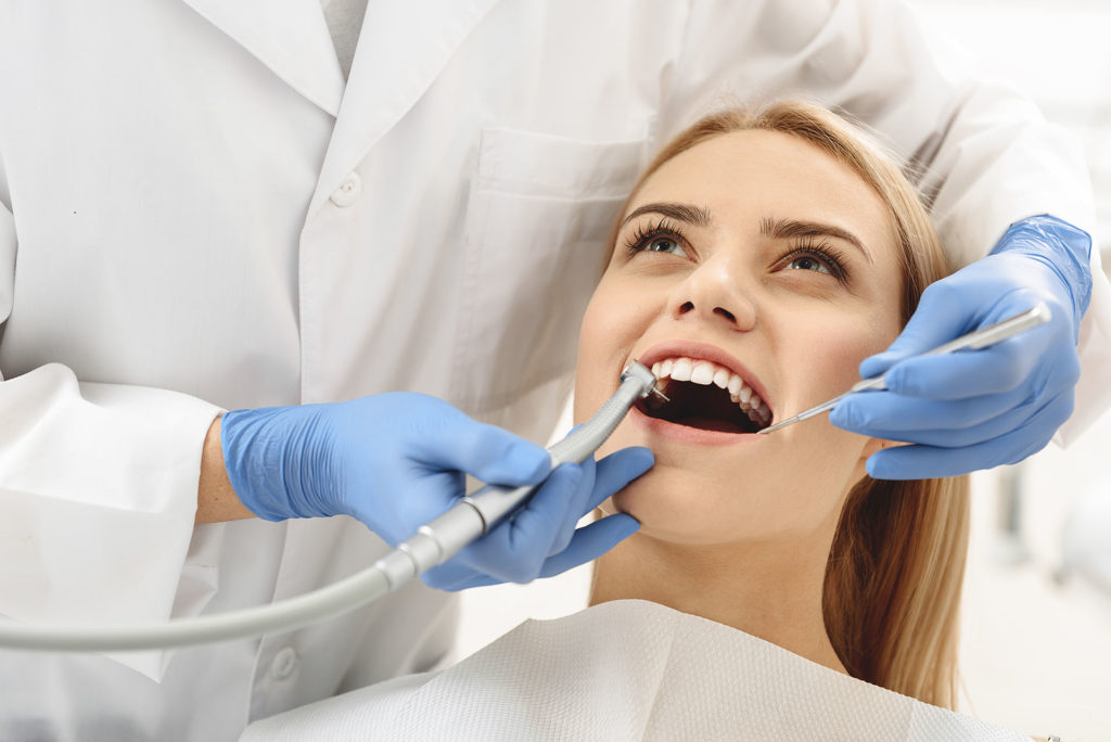 Dentist starting common operation of cleaning female mouth